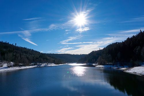 Gefrorener Fluss mit Schnee und Eis bei Sonnenschein unter blauem Himmel an der Nagoldtalsperre