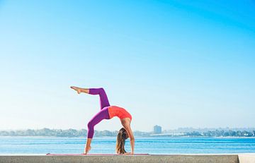 Jonge vrouw beoefent yoga op een smalle muur aan de kust van BeeldigBeeld Food & Lifestyle