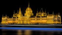 Hungarian parliament building at night with boat passing by