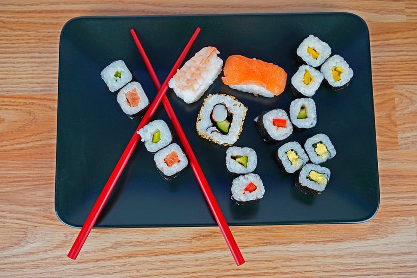 Sushi on black serving plate served with red chopsticks by Babetts Bildergalerie