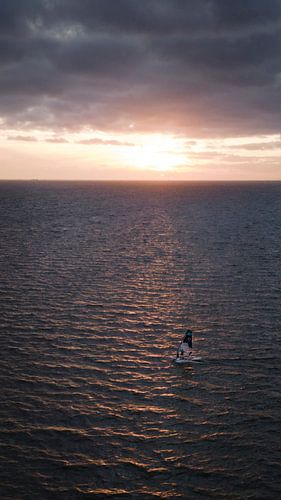 Un véliplanchiste en mer lors d'un coucher de soleil spectaculaire