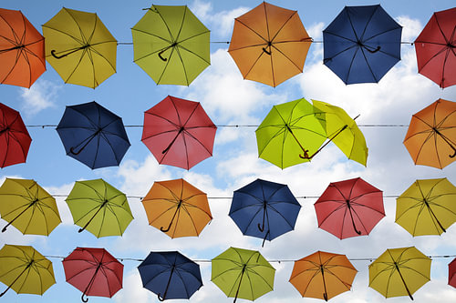 bunte hängende Regenschirme am Himmel, zwei flirten, Straßendekoration im Hintergrund