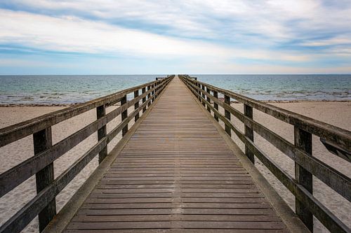 Holzsteg führt direkt über den Strand und das Meer zum Horizont, Konzept für den Weg in eine ungewis