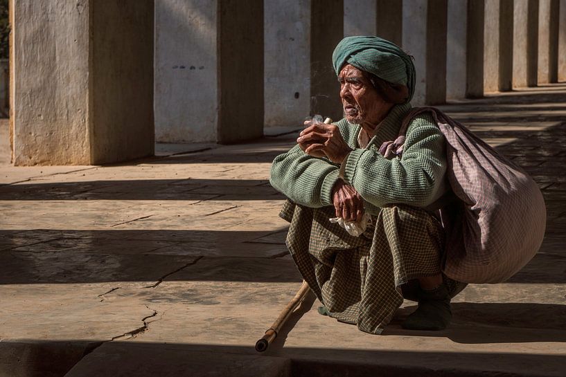 Bedelaar zit in de gang van een tempel in Bagan, Myanmar van Anges van der Logt