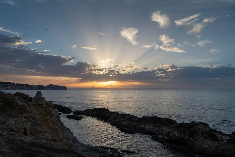 Dark rocks and sunrise behind clouds by Adriana Mueller