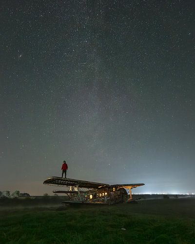 Persoon op verlaten vliegtuig onder sterrenhemel