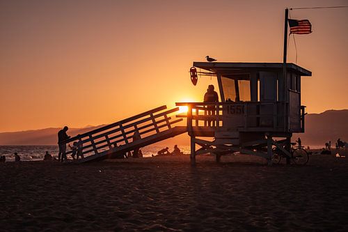 Zonsondergang met een strandwacht (Lifeguard) huisje langs de kust van Santa Monica Californië veren
