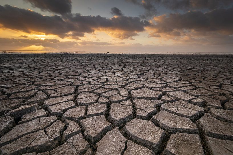 Trockenheit im Watt unter einem bedrohlichen Himmel bei Sonnenuntergang von Bram Lubbers