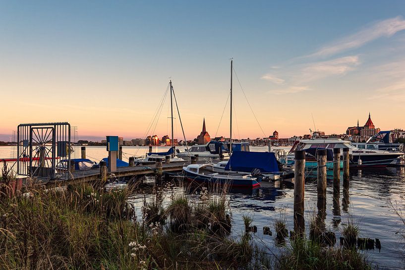 Uitzicht over de Warnow naar de Hanzestad Rostock in de avond van Rico Ködder