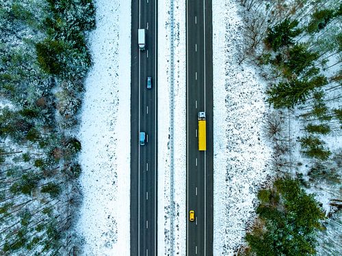 Snelweg door een besneeuwd boslandschap van bovenaf gezien