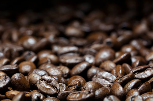 Kaffeehintergrund, dunkelbraun geröstete Bohnen, Nahaufnahme mit Details im Vordergrund, verschwomme
