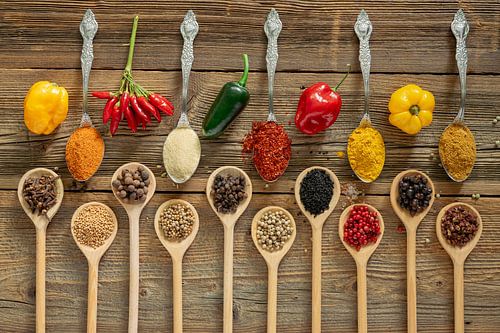 Kleurrijke chilipepers en exotische kruiden op hout