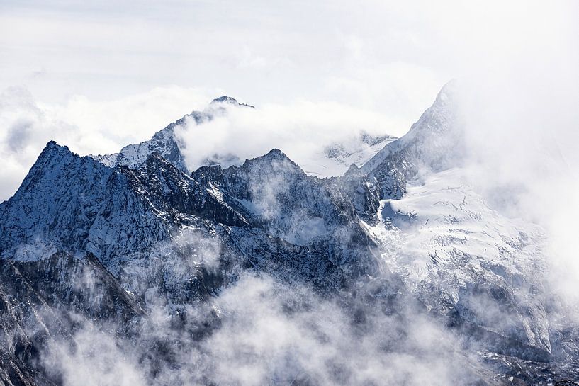 Hoge bergtoppen in de alpen omringd door wolken van Hidde Hageman