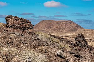 Landschap Lanzarote met lava rotsblokken op de voorgrond.