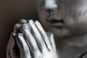 Namasté. Gros plan des mains et du visage d'un Bouddha en argent sur Birgitte Bergman