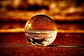 Blick durch die Glaskugel am Strand. Meer und Himmel im Hintergrund