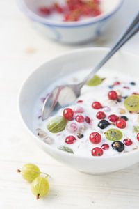 verse bessen en kruisbessen met natuurlijke yoghurt in een kom, gezond zomerontbijt of dessert op ee