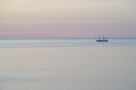 Zeilschip vlak voor zonsopgang tijdens het blauwe uur op rustig water onder een pastelkleurige hemel van Tomherkules