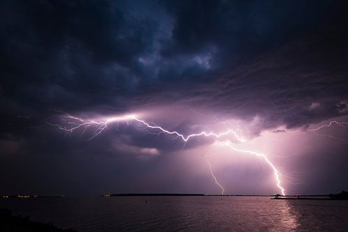 Bliksem in de donkere nachtelijke hemel boven een meer in de zomer