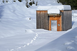 Bâtiment en bois recouvert de neige d'une petite centrale hydroélectrique en hiver, dans la neige profonde sur Tomherkules