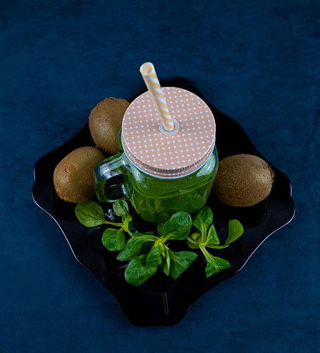 Bladsalade en kiwi smoothie op zwart bord versierd met kiwi en veldsla