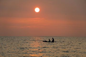 Vader en zoon, bij zonsondergang, peddelend op zee van Simone Kuijpers