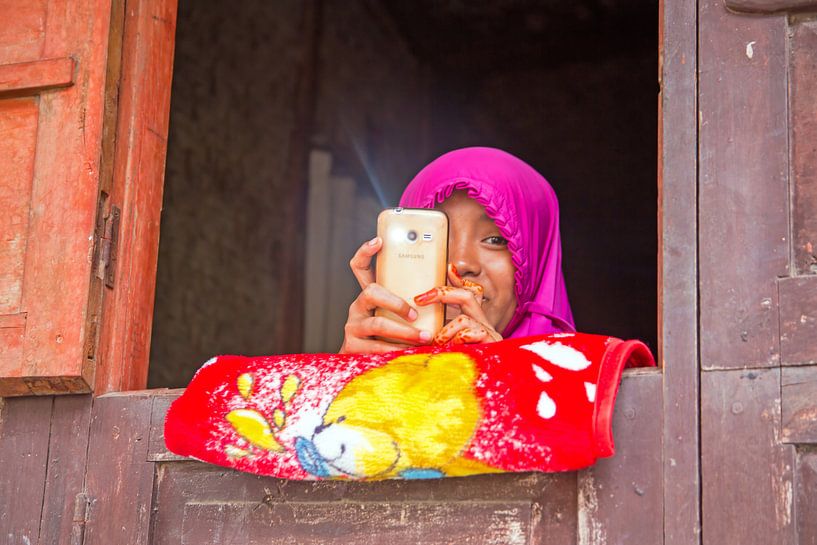 Lombok, Indonesie: Jong en ondeugend meisje met haar mobiele telefoon van Eye on You