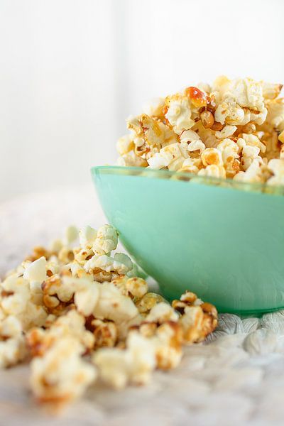 Vers gemaakte popcorn ligt in een kop op een tafel. van Edith Albuschat