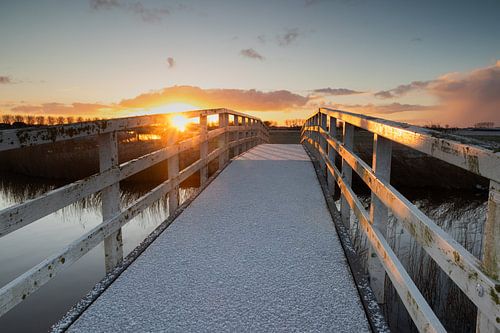 Met sneeuw bedekte witte boogbrug in de ochtendzon.