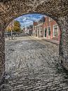 Doorkijkje vanuit de poort in de stadsmuur op een straat in Sloten, Friesland. van Harrie Muis thumbnail