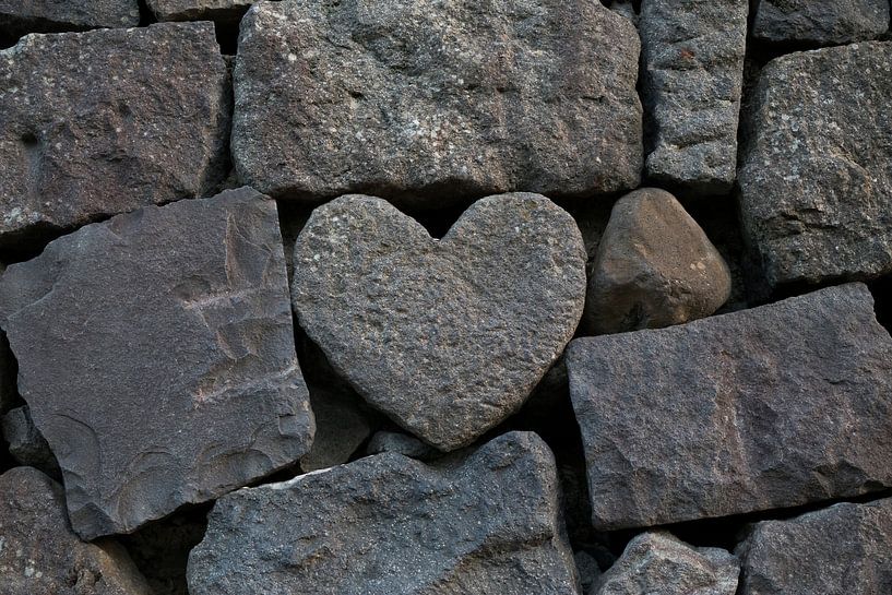 Herzförmiger Stein in einer Mauer mit groben grauen Steinen von Frans Rombout