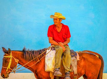 Mann auf Pferd vor blauer Wand in Kuba