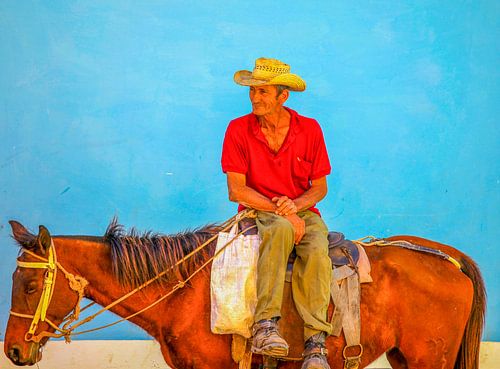 Man op paard voor  blauwe  muur in Cuba