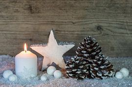 White Christmas candle decoration with snow, ornaments and wood background by Alex Winter