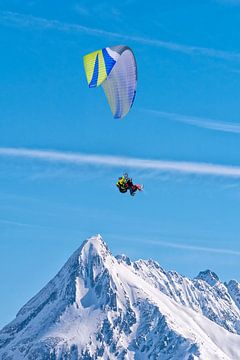 Paragliden boven de besneeuwde bergtop