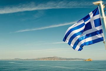 Griechische Flagge fliegt über dem Meer mit einer Insel im Hintergrund von WorldWidePhotoWeb