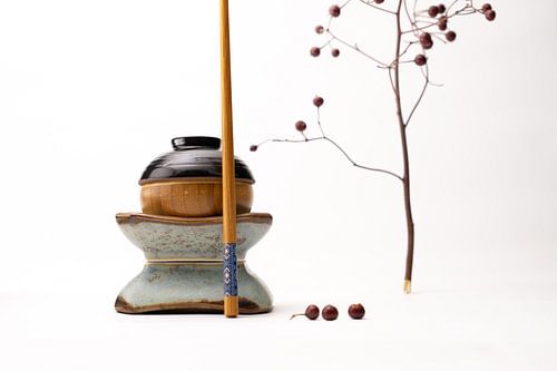 Stilleven van kopjes en eetstokje als Japans figuur met takjes en besjes