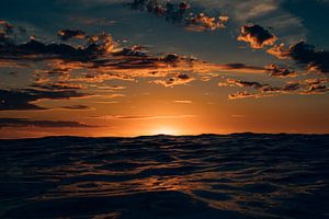 The setting sun hides behind a high wave at the North Sea beach of Terschelling by Alex Hamstra