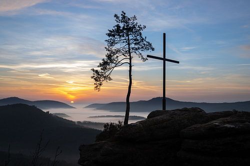 De Rötzenfels, een landschapsopname van een zandsteenrots met een kruis en een boom, zonsopgang met 