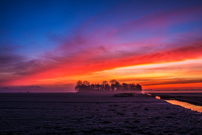 Vuurrode zonsopgang in de polder van Ton de Koning
