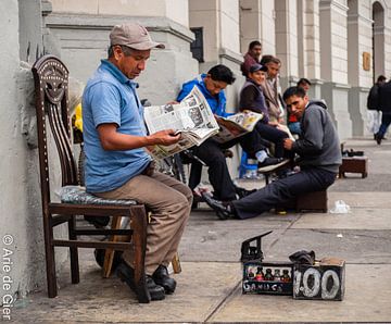 Un cireur de chaussures lit le journal à Lima, au Pérou. sur Arie Arie de Gier