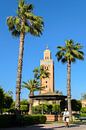Gebakjesverkoper in park met palmbomen voor minaret Koutoubia moskee in Marrakech Marokko van Dieter Walther thumbnail