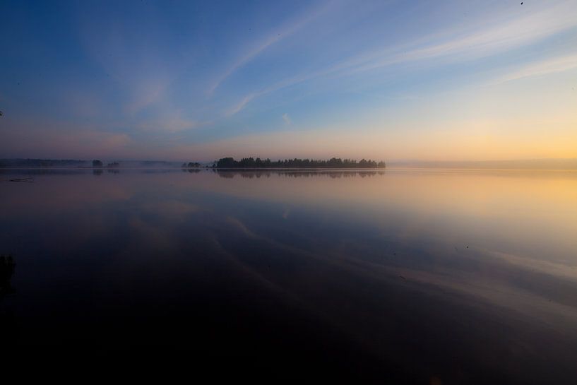 De dageraad op het meer. De blauwe en scharlakenrode hemel wordt gereflecteerd in het stille water v van Michael Semenov