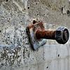 Une vis rouillée dans un mur de béton sur Maud De Vries