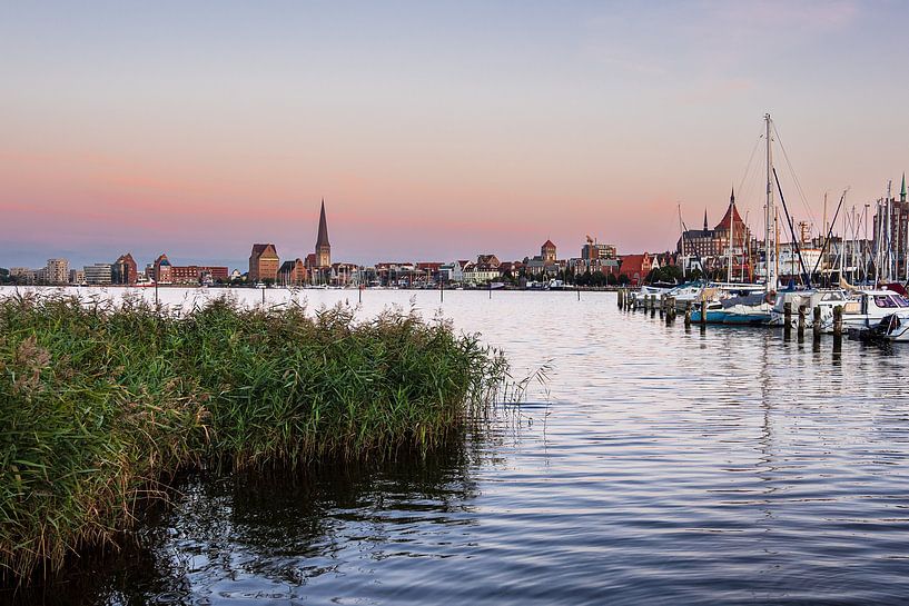 Uitzicht over de Warnow naar de Hanzestad Rostock in de avond van Rico Ködder
