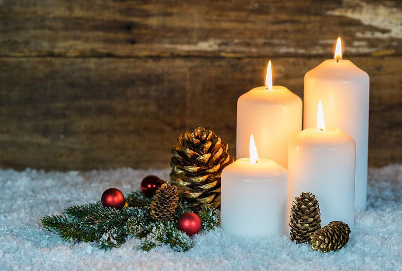 Quatre bougies allumées avec une décoration naturelle sur de la neige avec un fond en bois par Alex Winter
