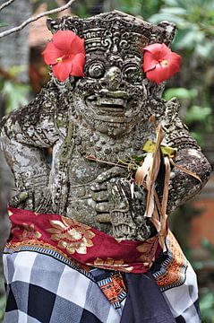 Statue adorned with red flowers in Ubud by Frank Photos