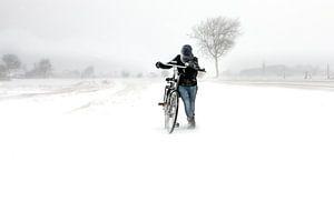 Meisje met fiets in sneeuwstorm in Zeeland van Wout Kok