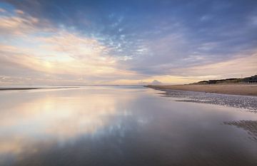 Reflecties op een nat strand bij zonsondergang