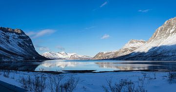 Zicht op het Fjord Vagbotn in de Atlantische Oceaan met sneeuw, bergen en zee bij Tromso Noorwegen van Leoniek van der Vliet